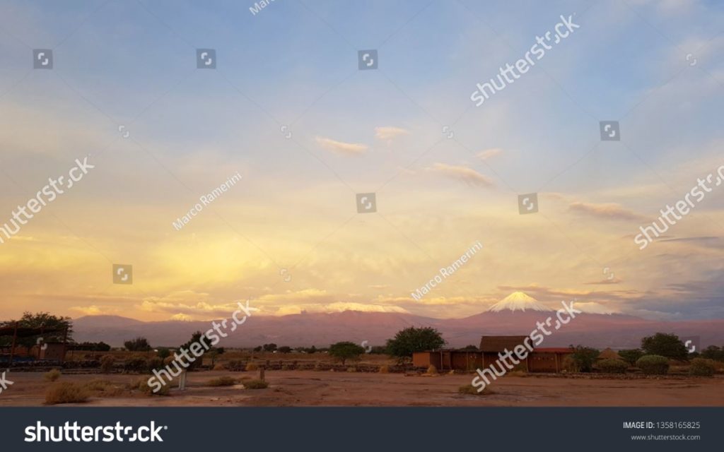 O por do sol ilumina-se na paisagem estéril e desolada do deserto de Atacama com os picos dos vulcões nevado da Cordilheira de Andes no fundo. Autor e Copyright Marco Ramerini